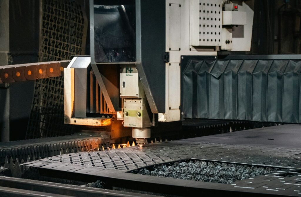 A CNC cutting machine operates on a metal sheet, creating precise patterns with a focused laser. This showcases advanced manufacturing technology.